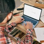 a woodworker in a workshop uses a laptop for furniture design planning and project management